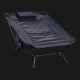 TieGear Base Lounger low-profile camp chair with hammock-style recline, lightweight frame, and durable fabric set up at a campsite.